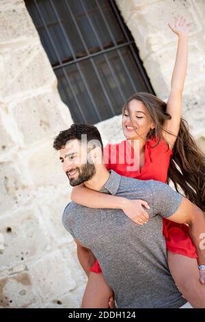 Porträt eines glücklichen jungen Paares, das eine Huckepack-Fahrt genießt. Stockfoto