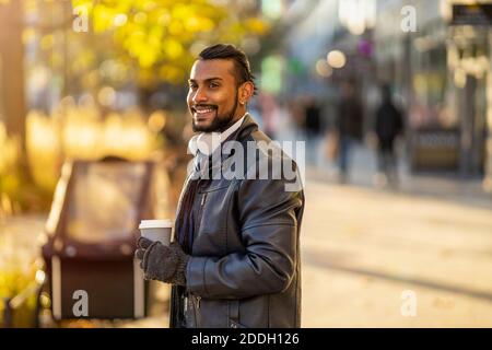 Hübscher junger Mann, der auf der Straße Kaffee trinkt Stockfoto