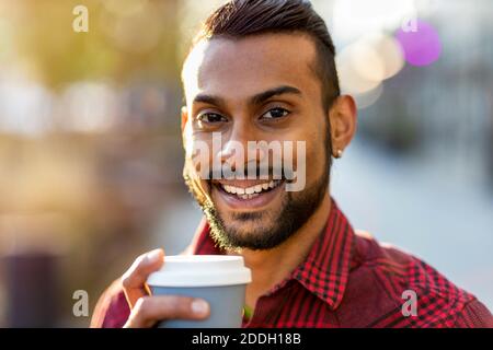 Hübscher junger Mann, der auf der Straße Kaffee trinkt Stockfoto