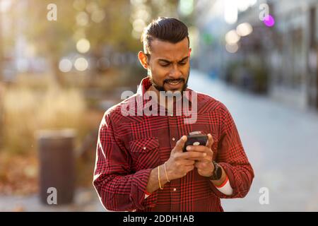 Hübscher junger Mann mit Handy auf der Straße Stockfoto