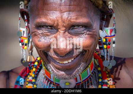 Masai Ältester trägt traditionellen Schmuck und Kleidung lächelnd für die Kamera Stockfoto