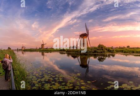 Fotograf, der Windmühlen bei Sonnenuntergang in Kinderdijk, Niederlande fotografiert Stockfoto