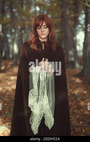 Schöne Frau allein im Wald. Mittelalterliches Kleid und Umhang Stockfoto