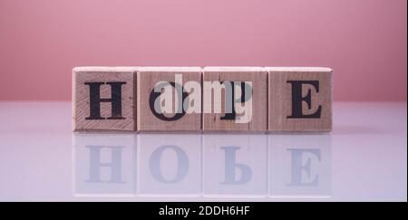 Text HOFFNUNG auf Holz Würfel Blöcke. Die Buchstaben HOPE auf den Würfeln in schwarzen Buchstaben auf einer Glasoberfläche isoliert geschrieben. HOFFNUNG Text für Ihre Desing. Stockfoto