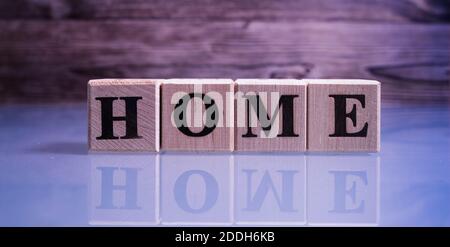 Text HOME auf Holz Würfel Blöcke. Die Briefe ZU HAUSE auf den Würfeln in schwarzen Buchstaben isoliert auf einer Glasoberfläche geschrieben. HOMEText für Ihr Design. Stockfoto