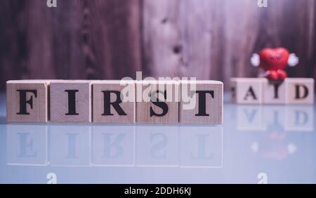 Text ERSTE HILFE auf Holzwürfelblöcke. Die Buchstaben ERSTE HILFE auf den Würfeln in schwarzen Buchstaben isoliert auf einer Glasoberfläche geschrieben. ERSTE-HILFE-Text für Ihr Stockfoto