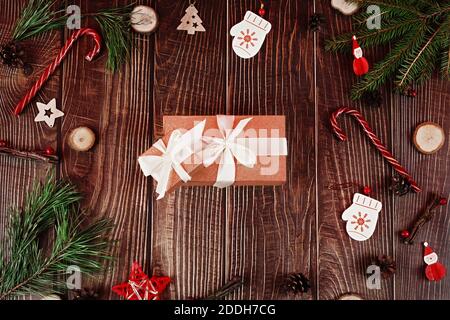 Eingewickelte Glitzer-Geschenkbox mit weißem Band auf dunklen Holzbrettern mit Tannenbaum und natürlichen weihnachtsdekorationen. Konzept für das neue Jahr. Stockfoto