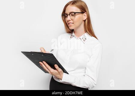 Bild von einer jungen schwangeren Geschäftsfrau mit Brille, nachdenkliche Mädchen hält einen Ordner mit Dokumenten in der Hand und schreibt Berichte, isoliert auf weißem Hintergrund Stockfoto