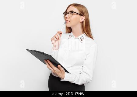 Bild einer jungen schwangeren Geschäftsfrau mit Brille, nachdenkliches Mädchen hält einen Ordner mit Dokumenten in den Händen, Blick auf den leeren Raum in der BA Stockfoto