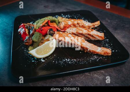 Ein Teller gegrillter Lachs mit Gemüse und Zitrone Stockfoto