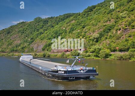 Ein sehr langer kommerzieller Lastkahn, der Waren auf dem Fluss transportiert Rhein in Deutschland mit einem Hintergrund von Bäumen bedeckten Hängen Stockfoto