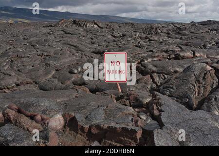 Ein erstarrter Lavastrom über das Land und eine Straße an der Ostküste der Hawaii-Insel mit einem Parkplatzschild fast begraben, Hawaii Stockfoto