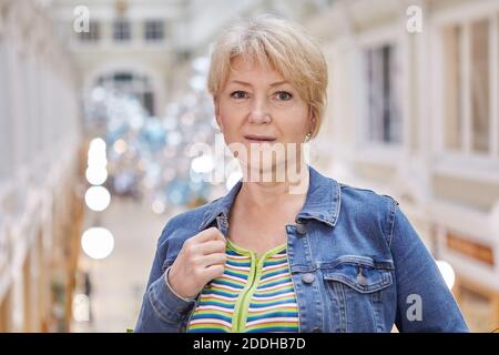 Ernst schön im Alter Frau Porträt beim Spaziergang im Einkaufszentrum. Attraktive blonde alte Dame in der Fachgalerie. Stockfoto