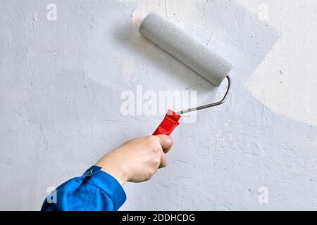 Hausmaler verwendet Farbwalze für die Malerei verputzte Wand. Handwerker bedeckt Wände durch Farbe mit Arbeitswerkzeug. Stockfoto