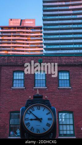 Distillery Town, Toronto, Kanada - July 2014 - Alte Uhr in Gegenüberstellung zu alten und modernen Gebäuden Stockfoto