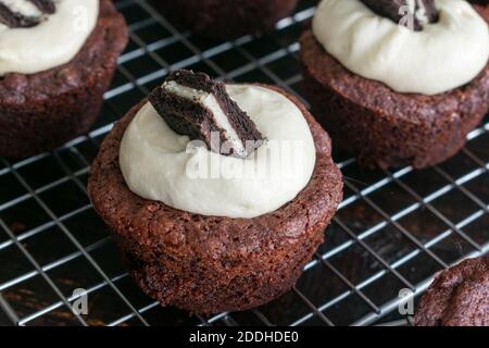 Oreo gefüllte Brownie Cups: Brownie Tassen gefüllt mit einem Sandwich-Cookie und gekrönt mit Zuckerguss auf einem Draht Kühlgestell Stockfoto