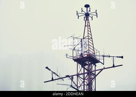 Metallturm mit Antennen für verschiedene Zwecke vor dem Hintergrund Von einem rauchigen Himmel Stockfoto