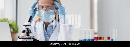 Müde Wissenschaftler in medizinischen Maske und Brille Kopfschmerzen im Labor, Banner Stockfoto