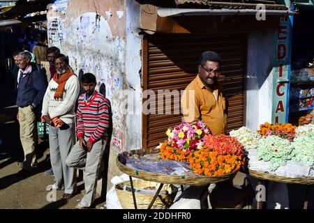 Ooty, Tamil Nadu, Indien - Januar 2017: Mann verkauft Blumen für religiöse Spenden auf der Straße. Hinduismus Tradition. Stockfoto