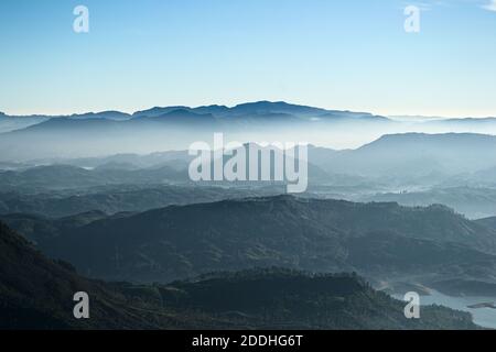 Gebirgslandschaft mit frischen Morgenfarben. Blick vom Sri Pada Gipfel (Adam's Peak) auf das Tal im Nebel und dem Maskeliya Reservoir Stockfoto