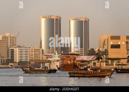 Dubai, VAE - 1. September 2020: Zwei Abra, das traditionelle hölzerne Fährschiff, segeln auf dem Creek mit dem Rolex Twin Tower im Hintergrund im Bur D Stockfoto