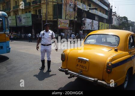 Kolkata, Indien - März, 2014: Straßenpolizei Mann versucht direkten Verkehr auf der Straße in der Nähe der traditionellen retro-Taxi in Kalkutta Stockfoto