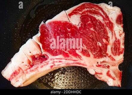 Ein Blick von oben auf ein rohes Steak, das auf einem kocht Schwenken Sie unter die Lichter Stockfoto