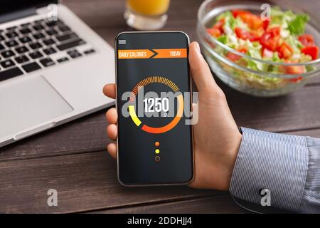 Smart Essen und Diät-Planung Konzept. Mann hält Smartphone mit geöffneter App zum Zählen der täglichen Kalorien, Nahaufnahme Stockfoto