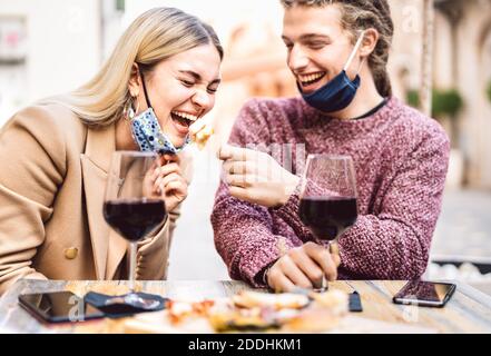 Junges Paar in der Liebe tragen offene Gesichtsmasken Spaß haben In der Weinbar im Freien - Glückliche Reisende Freunde genießen Mittagessen Gemeinsam im Restaurant Garten