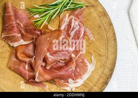 Prosciutto Scheiben auf rustikalem Holzbrett mit Rosmarin Zweige Top Bild mit Kopierbereich anzeigen Stockfoto