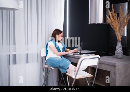 Junge Frau, die am Esstisch arbeitet. Wohnküche im Hintergrund. Stockfoto
