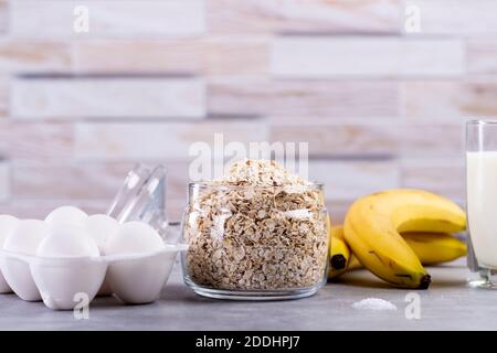 Haferpfannkuchen mit Banane. Schritt für Schritt Kochvorgang. Zutaten Draufsicht. Bananen, Milch, Eier, Hafer, Salz. Holztisch Hintergrund. Speicherplatz kopieren Stockfoto