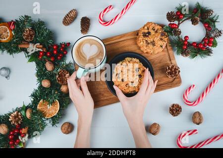 Weibliche Hand hält Haferkeksen mit getrockneten Früchten auf grauem Hintergrund. Flach liegend, Draufsicht Stockfoto