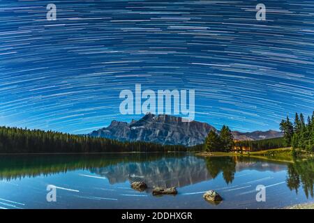 Schöne Sternwege über dem Mount Rundle von Two Jack Lake bei Nacht, Sternenhimmel spiegelte sich in der Wasseroberfläche. Landschaft im Banff National Park Stockfoto