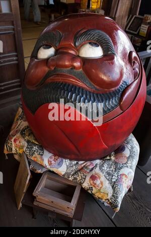 Vertikale Hochwinkelansicht einer runden Daruma-Holzskulptur im buddhistischen Tempel Daisho-in, Miyajima, Japan Stockfoto