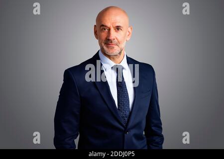 Kurzaufnahme eines leitenden Geschäftsmannes, der Anzug und Krawatte trägt, während er auf einem isolierten grauen Hintergrund steht. Speicherplatz kopieren. Stockfoto