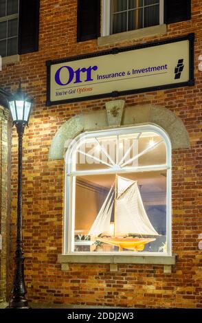 Ein Modell Segelboot wird durch ein Fenster bei Orr Insurance & Investment Company am Courthouse Square in der Abenddämmerung in Downtown Goderich, Huron County, Ontar gesehen Stockfoto