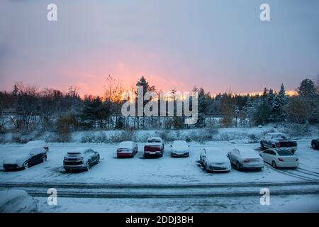 Autos geparkt auf einem Grundstück außerhalb eines Gebäudes während einer Frostiger, schöner Sonnenuntergang im Winter Stockfoto