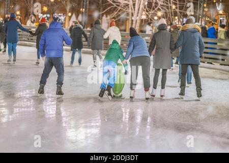 Weihnachten, Winter und Freizeit, Sportkonzept, glückliche Freunde und Familien auf der Eisbahn, Abend im Freien, Feiertagsbeleuchtung Stockfoto