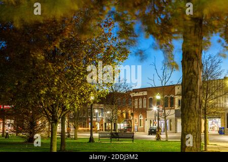 Herbstlaub im Courthouse Park auf dem Courthouse Square in der Abenddämmerung in Downtown Goderich, Huron County, Ontario, Kanada. Stockfoto
