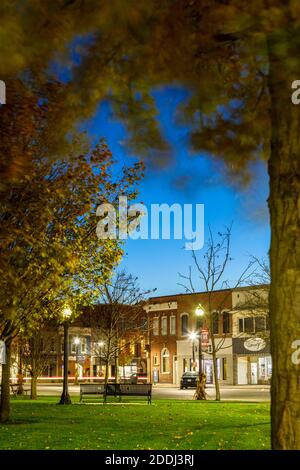 Herbstlaub im Courthouse Park auf dem Courthouse Square in der Abenddämmerung in Downtown Goderich, Huron County, Ontario, Kanada. Stockfoto