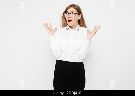 Das Bild einer jungen schwangeren Geschäftsfrau, die eine Brille mit kabellosen Kopfhörern trägt, zeigt ein Missverständnis auf weißem Hintergrund Stockfoto