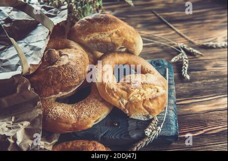 Hausgemachte Brötchen Brezeln in einer Papiertüte auf einem dunklen Holztisch. Handgemachtes gebackenes Brot aus nächster Nähe. Umweltfreundliche Verpackung. Stockfoto