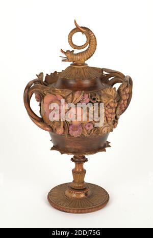 Standing Cup and Cover, 1800-1900 Dies ist ein gut gemachtes Beispiel für eine dekorative Tasse und Abdeckung, die aus Platane gedreht wurde. Die Dekoration ist aus einer Reihe von Schnitzereien aufgebaut, die dann zusammengeklebt und gedübelt wurden. Sozialgeschichte, Holz Stockfoto