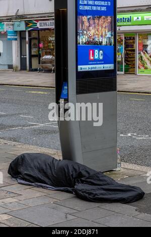 Obdachlose Person schlafen rau neben einem mobilen Gerät oder Handy-Ladegerät Laden Handy auf der Straße. Stockfoto