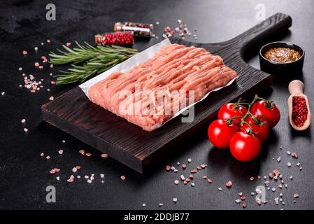 Frische rohe Hähnchenhackfleisch auf einem dunklen Holzschneidebrett. Vorbereitung für die Vorbereitung von Schnitzel Stockfoto