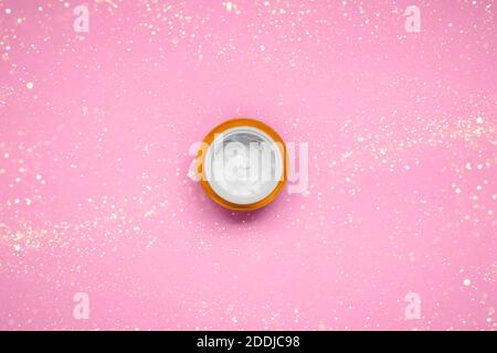 Natürliche nachhaltige Hautcreme auf rosa Hintergrund mit Weihnachten glitzert - Creme Textur in Behälter. Flach liegend, Platz für Text Stockfoto