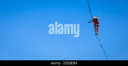 LANZO, ITALIEN - CA. OKTOBER 2020: Slackline-Athlet während seiner Performance. Konzentration, Balance und Abenteuer in diesem dynamischen Sport. Stockfoto