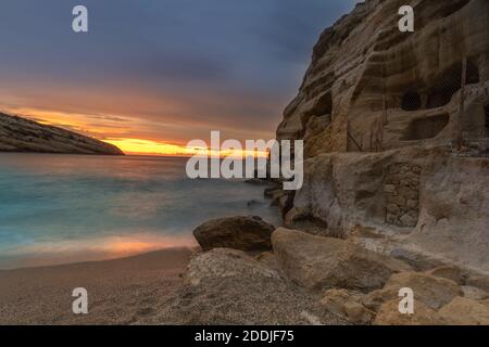 Sonnenuntergang neben den römischen Katakomben, die auf den Sandsteinklippen über dem Matala Strand, Kreta, Griechenland, geschnitzt wurden. In römischer Zeit wurden die Toten in ihnen begraben, Stockfoto