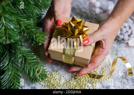 Schöne festliche Überraschung Box Geschenk golden mit einer Schleife Mädchen Halten in ihren Händen in der Nähe des weihnachtsbaums für neu Jahr und weihnachten Stockfoto